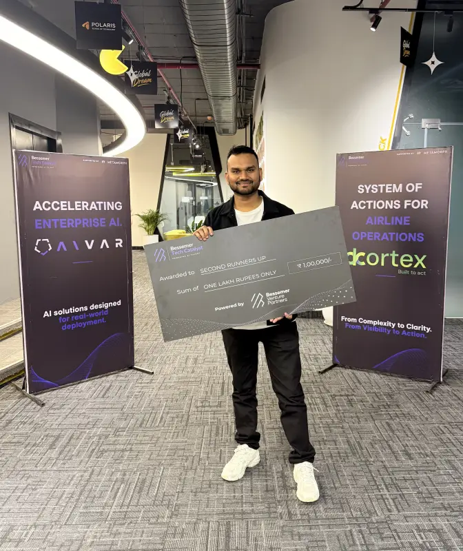 Deepak holding the runner-up cheque between Aivar and dCortex banners